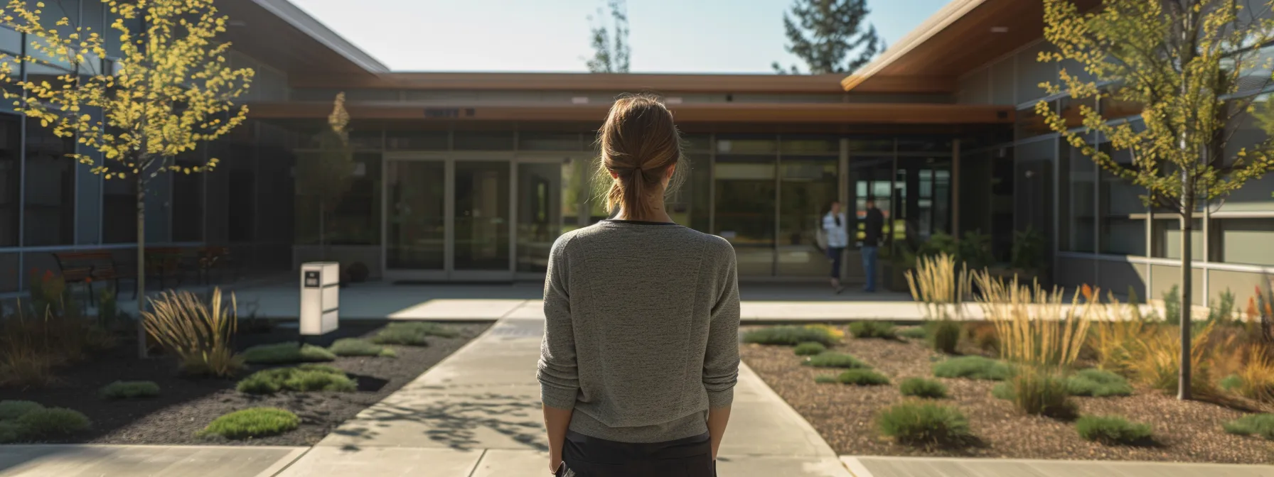 a person standing outside a modern, welcoming intensive outpatient treatment center, looking determined and hopeful.