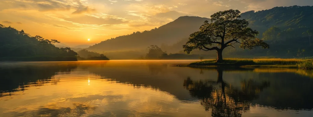 a vibrant sunrise casts a golden glow over a tranquil lake, reflecting the lush green mountains and a solitary tree standing gracefully at the water's edge.