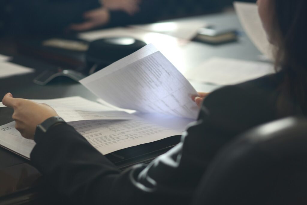 Hands flipping through a stack of paperwork at a desk in cinematic light