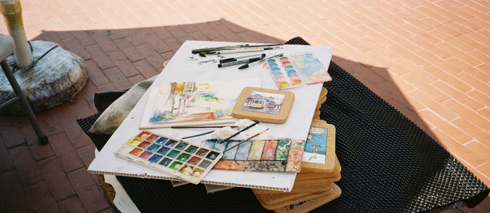 Art Therapy Activities for Anxiety: A Therapist's Guide 3 A set of watercolors with brushes and sketch pads in natural editorial light