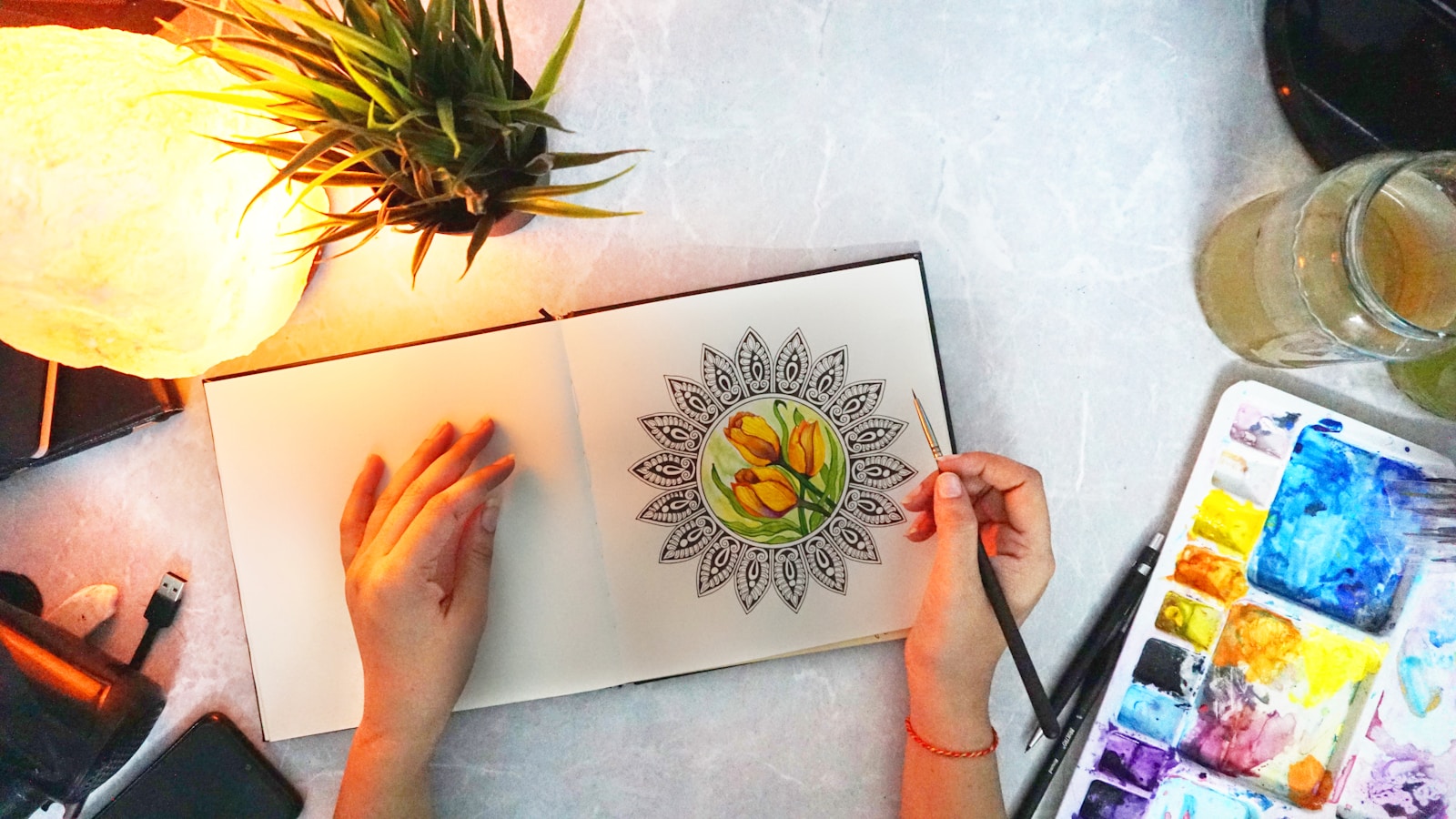 Art Therapy Activities for Anxiety: A Therapist's Guide 4 Hands holding up a completed mandala drawing in soft light