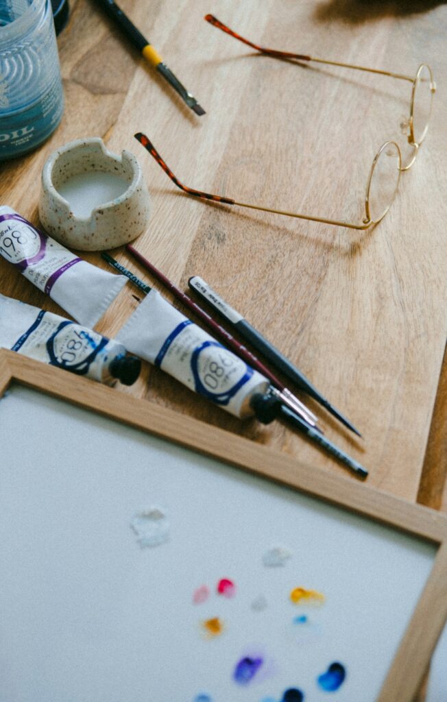 Art Therapy Activities for Anxiety: A Therapist's Guide 1 Watercolor brushes colored pencils and a sketchbook arranged on a wooden table in natural light