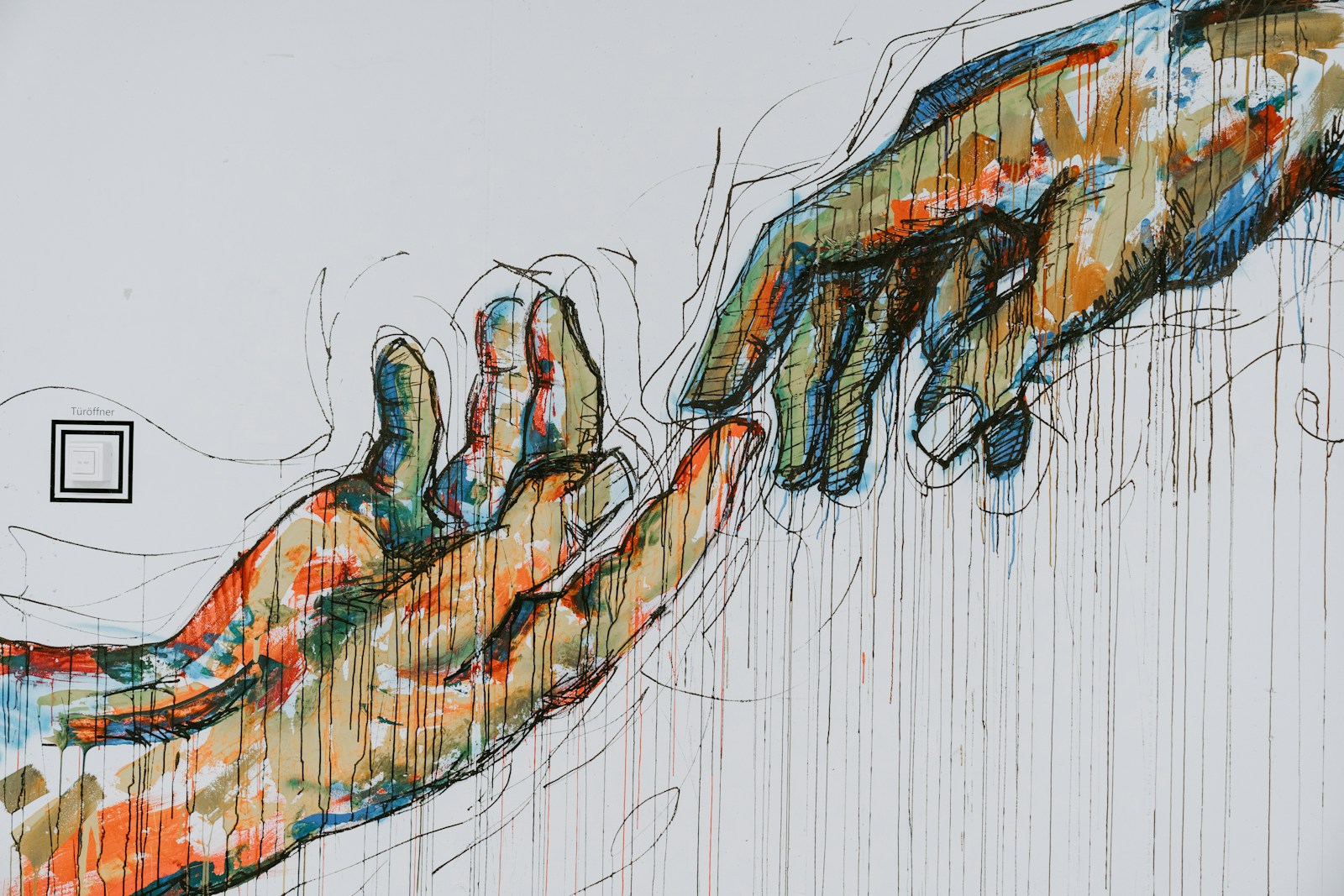 Two hands working together on a watercolor painting at a wooden table