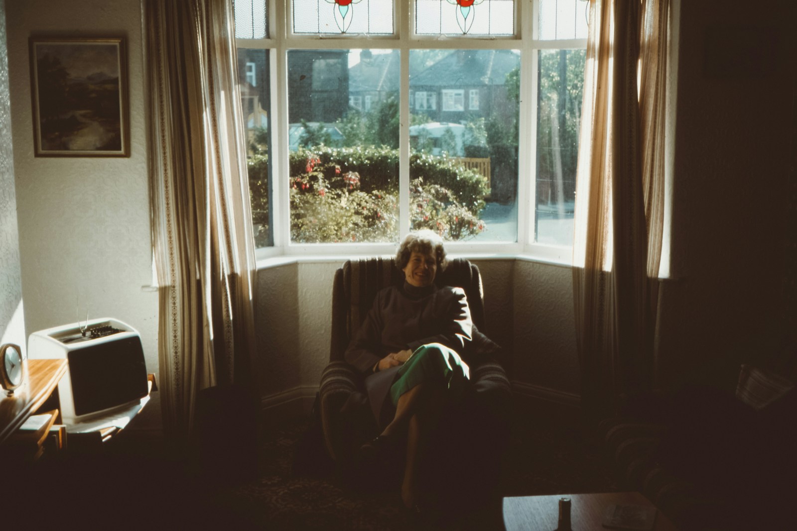 A woman by a window in neutral tones, peaceful expression