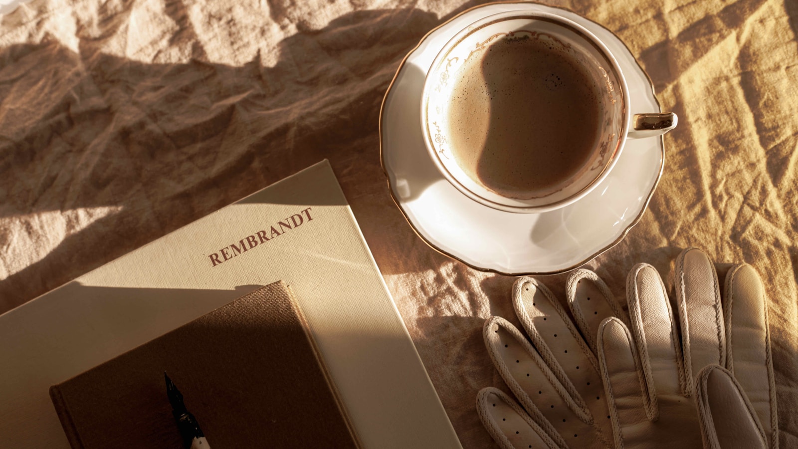 A book and coffee cup on a bed in cozy morning light
