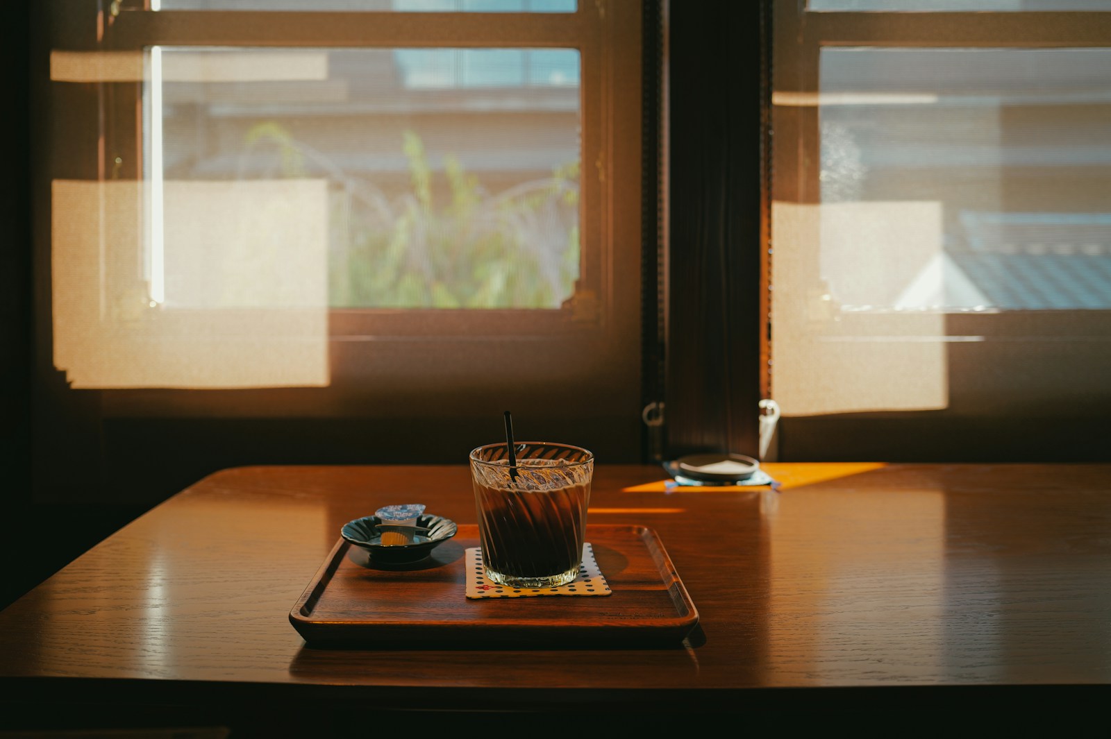 An iced coffee on a wooden table near a sunlit window