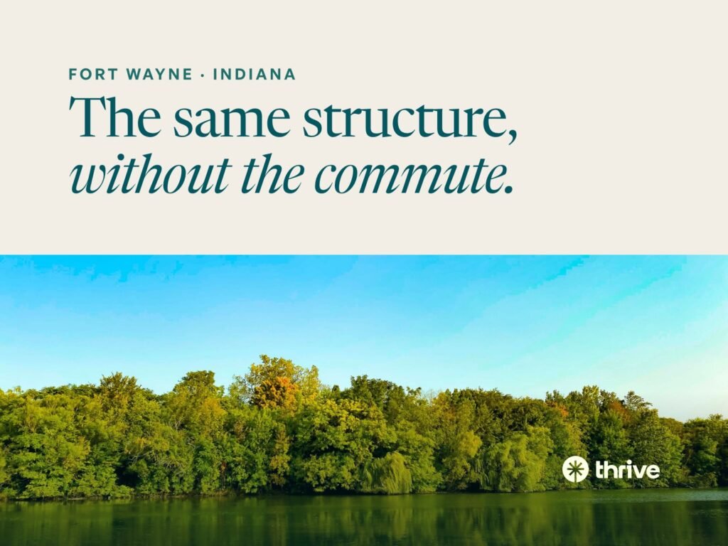 Fort Wayne · Indiana: The same structure, without the commute. Green trees reflected in still water under a blue sky. Thrive.