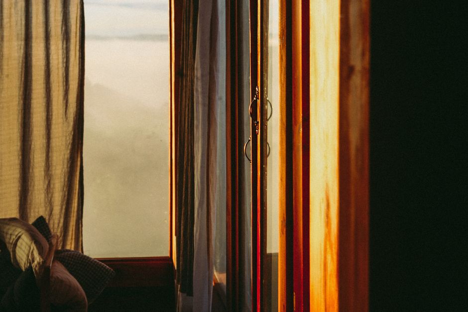 Warm interior scene with sunlight streaming through a window and curtain.