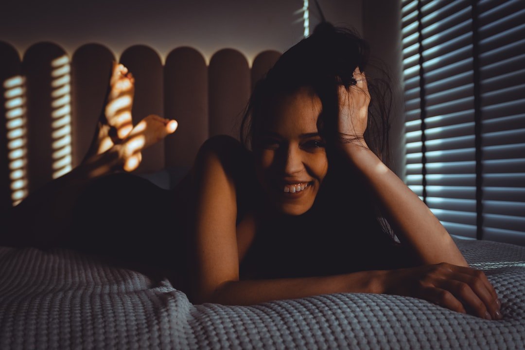 Smiling woman lying on bed with striped shadows.