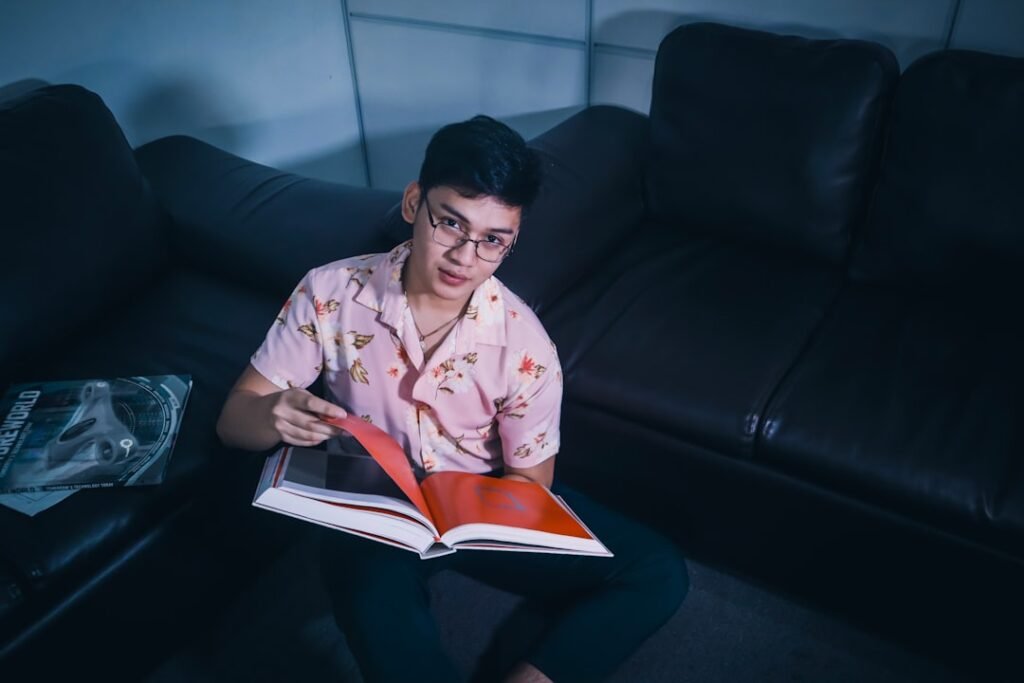 a man sitting on a couch reading a book.