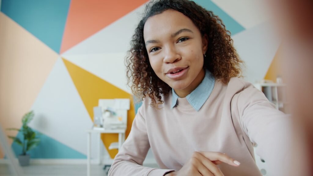 Portrait of Afro-American woman making video call from office talking waving hand enjoying friendly conversation smiling. People and communication concept.