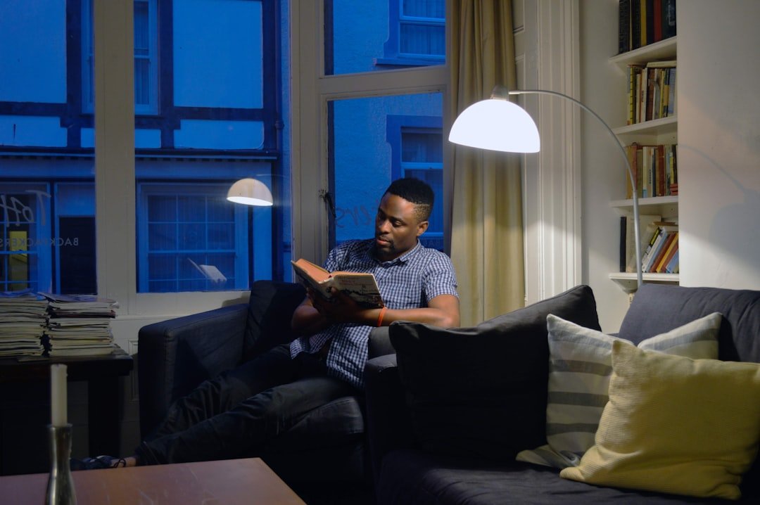 a man sitting on a couch reading a book.