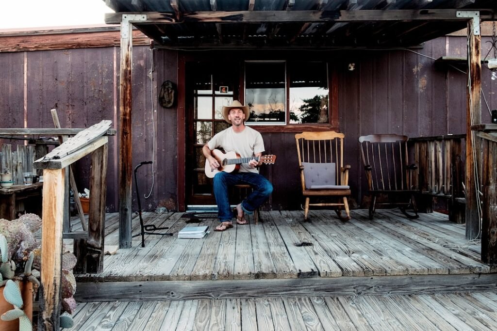 Acoustic guitarist playing on his porch in Pionnertown, California by laurenmacneish.com.