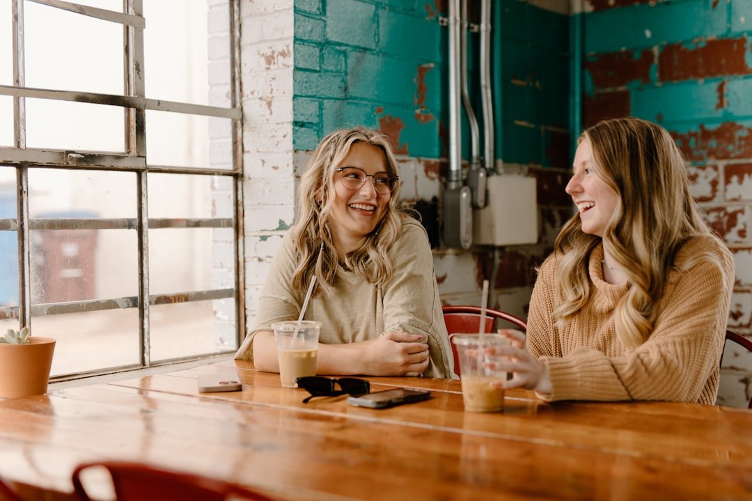 a couple of women sitting at a wooden table.