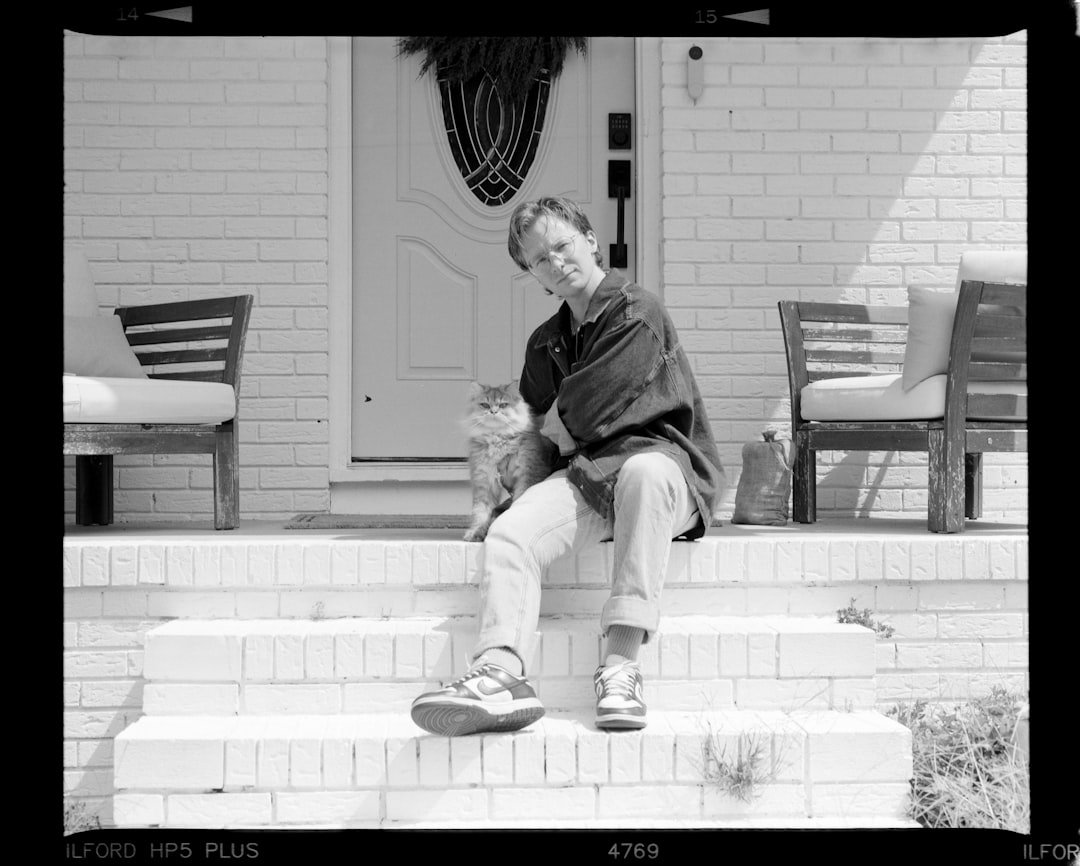 Man and cat sitting on porch steps.