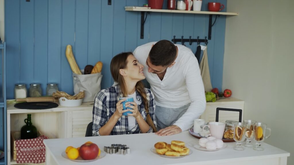 Attractive couple meet and kiss in the kitchen at breakfast time at home in the morning.