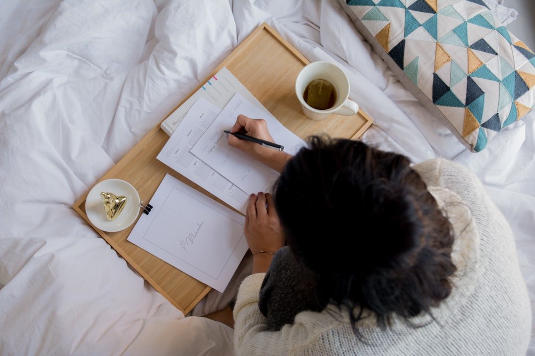 Virtual IOP in Gilbert, Arizona 6 person writing on white paper beside white ceramic mug on white textile.