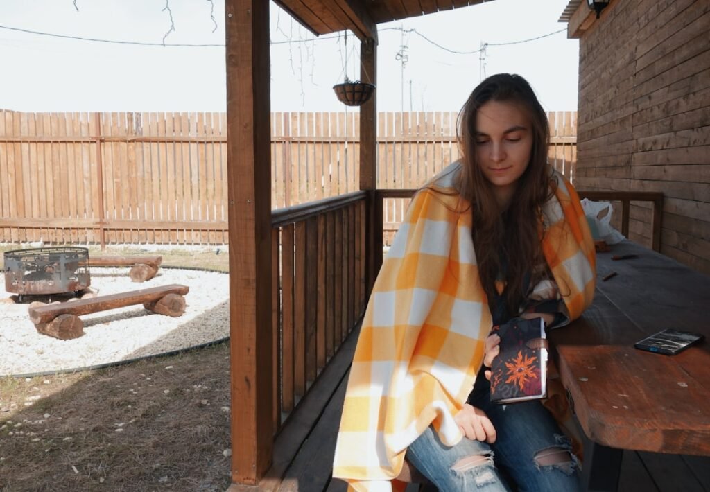 a woman sitting on a porch holding a book.