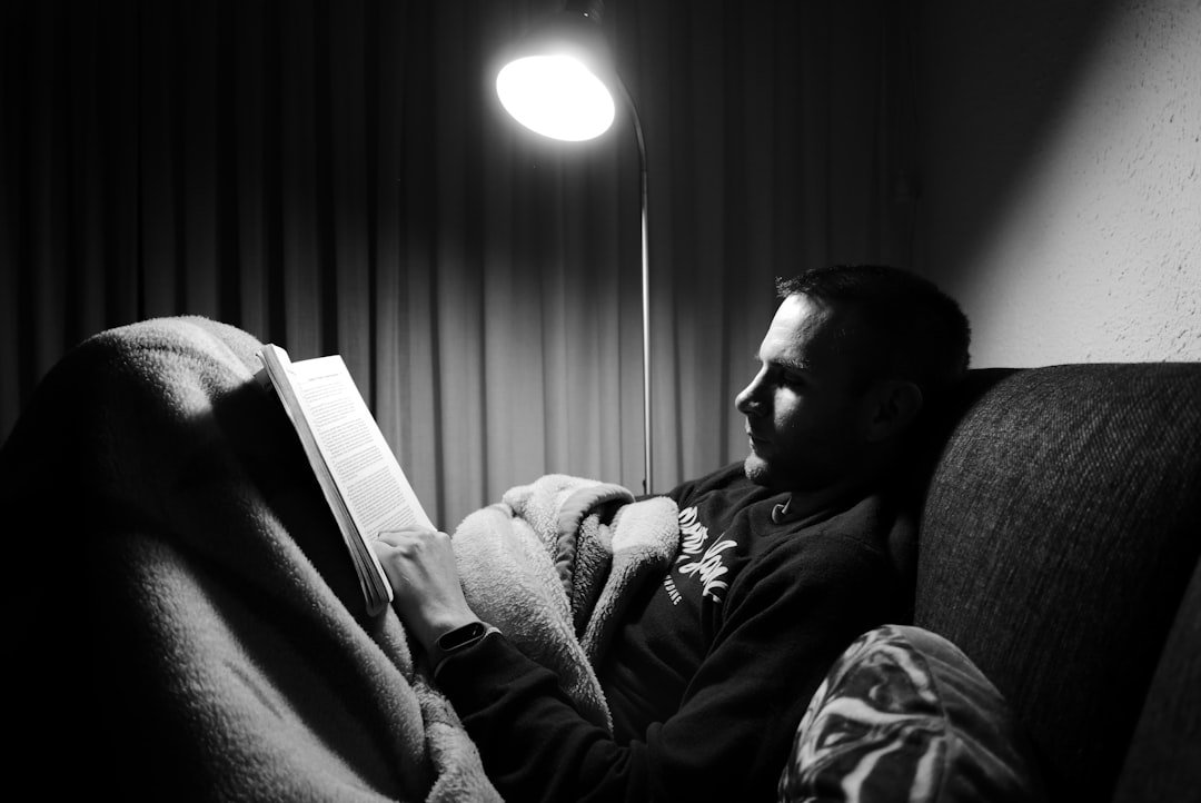 grayscale photo of man in jacket sitting on sofa.