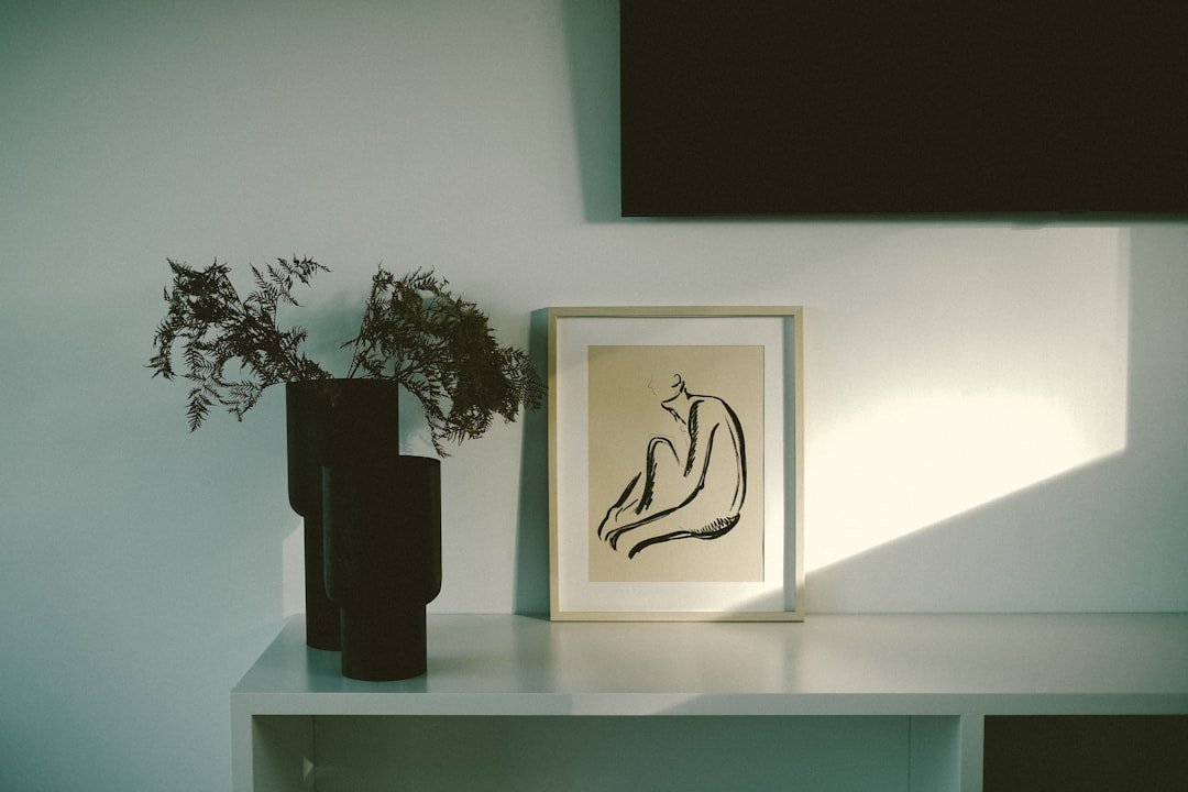 a vase with a plant in it next to a picture.