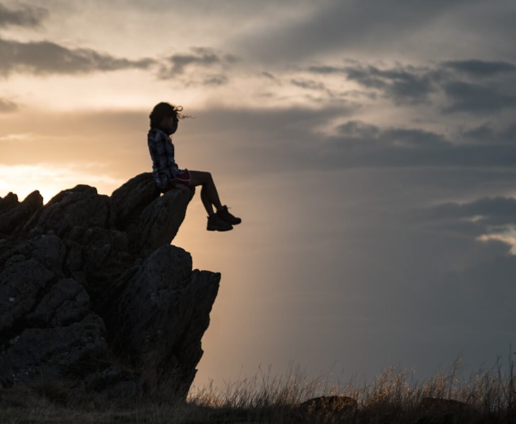 a person sitting on top of a large rock.