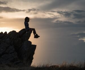 a person sitting on top of a large rock.