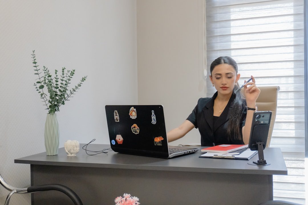 Woman working at desk with laptop and phone.