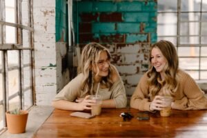 two women sitting at a table with drinks.