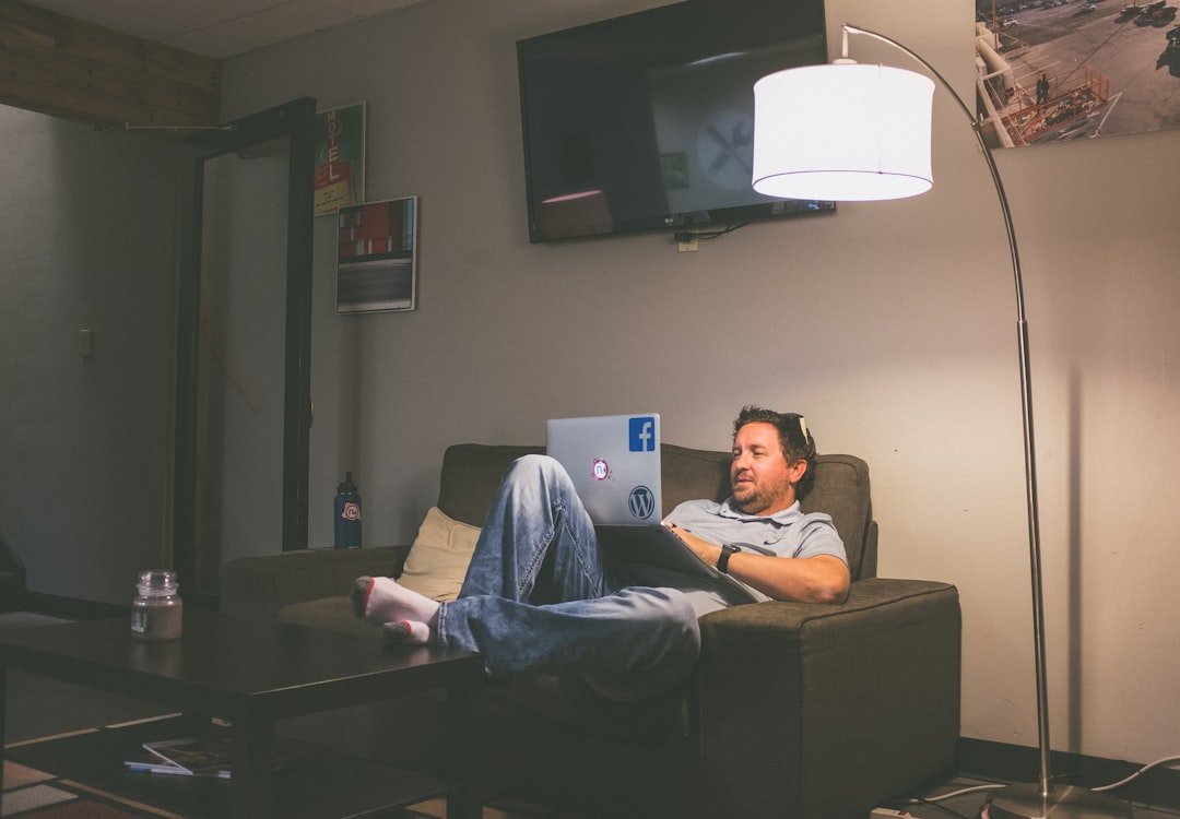 man lying on couch while using laptop computer.