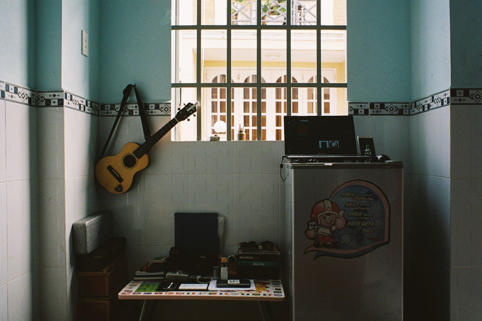 A home workspace featuring a guitar on the wall, a laptop, and a comfortable setup by the window.