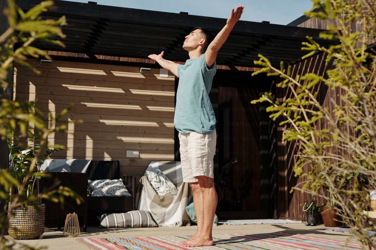 A man practicing yoga on a sunlit veranda, embracing a healthy lifestyle.