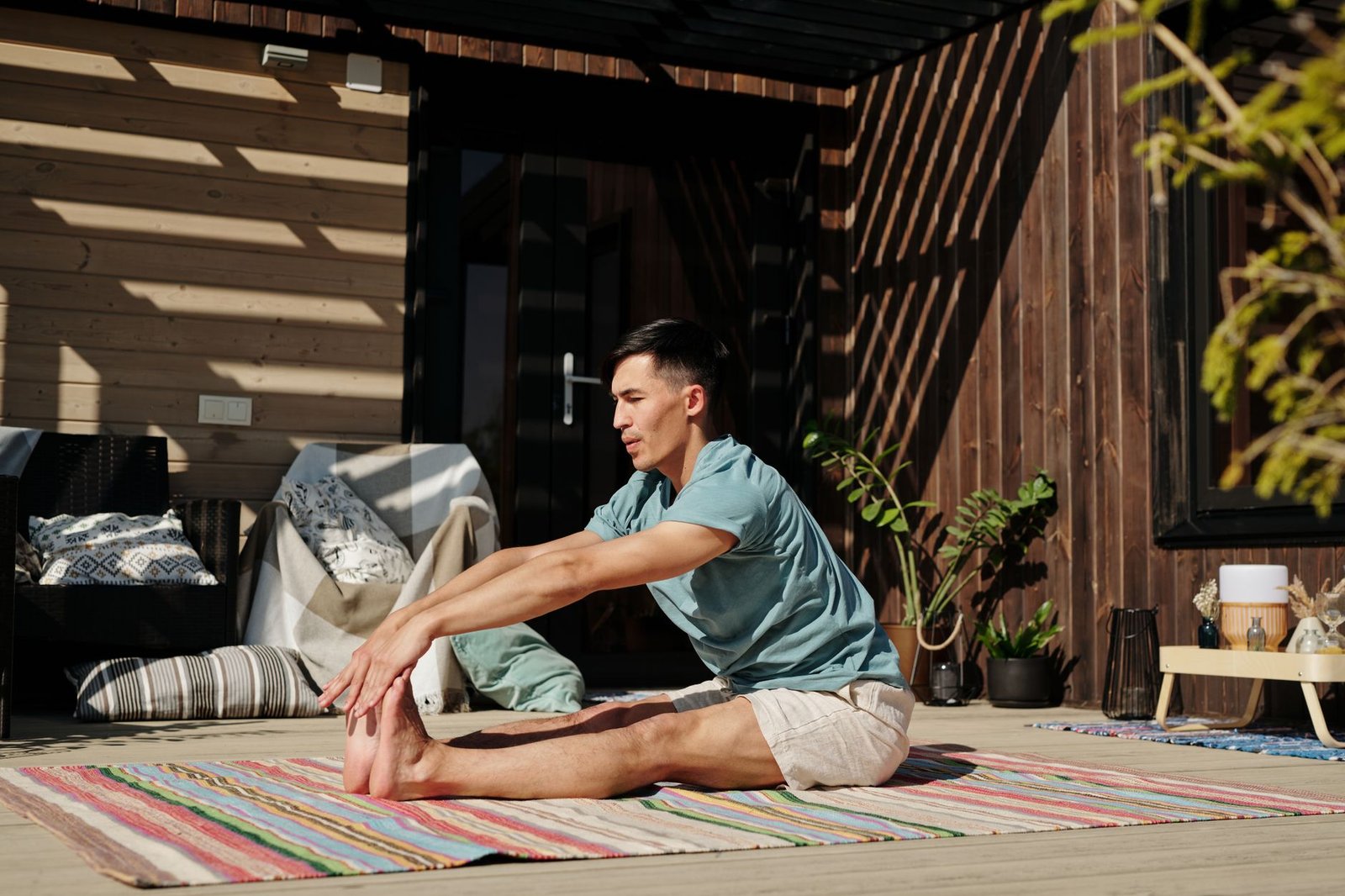 Young adult male stretching on a veranda during a sunny day, promoting a healthy lifestyle.