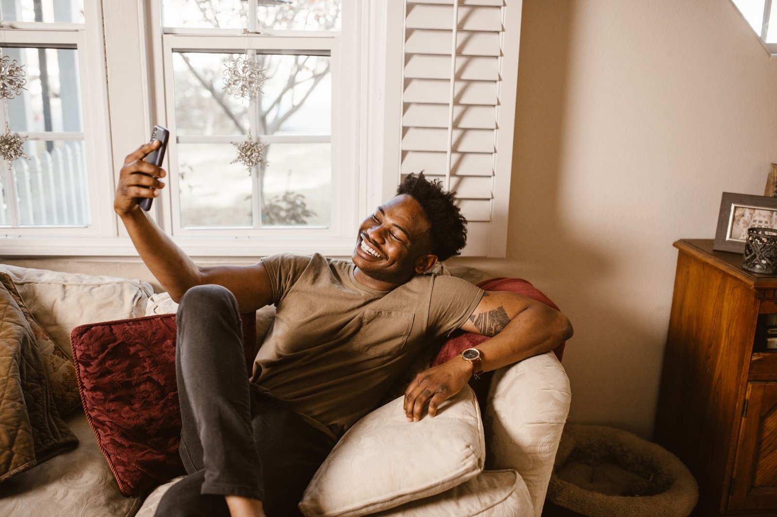 Anthem vs UnitedHealthcare for Mental Health in Indiana (2026) 8 A cheerful man takes a video call on the sofa, smiling and relaxed.