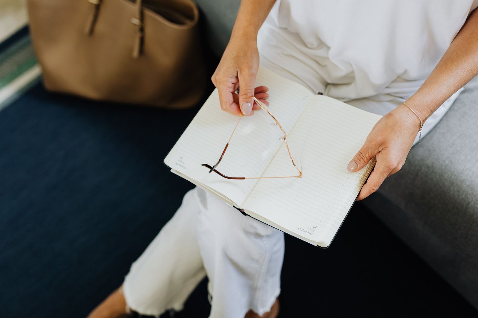Open Enrollment 2027 in Indiana: Picking a Plan for Mental Health 5 A woman sitting indoors holding glasses and a blank notebook, perfect for business or lifestyle themes.