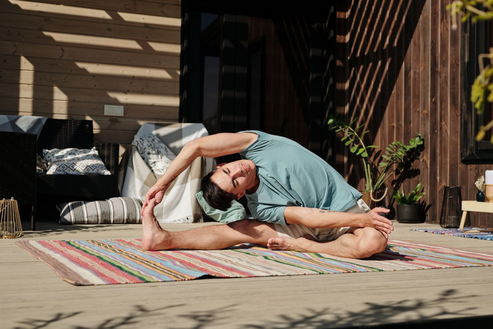 Open Enrollment 2027 in Indiana: Picking a Plan for Mental Health 6 Adult man in yoga pose stretching on a colorful mat on a sunny outdoor veranda.