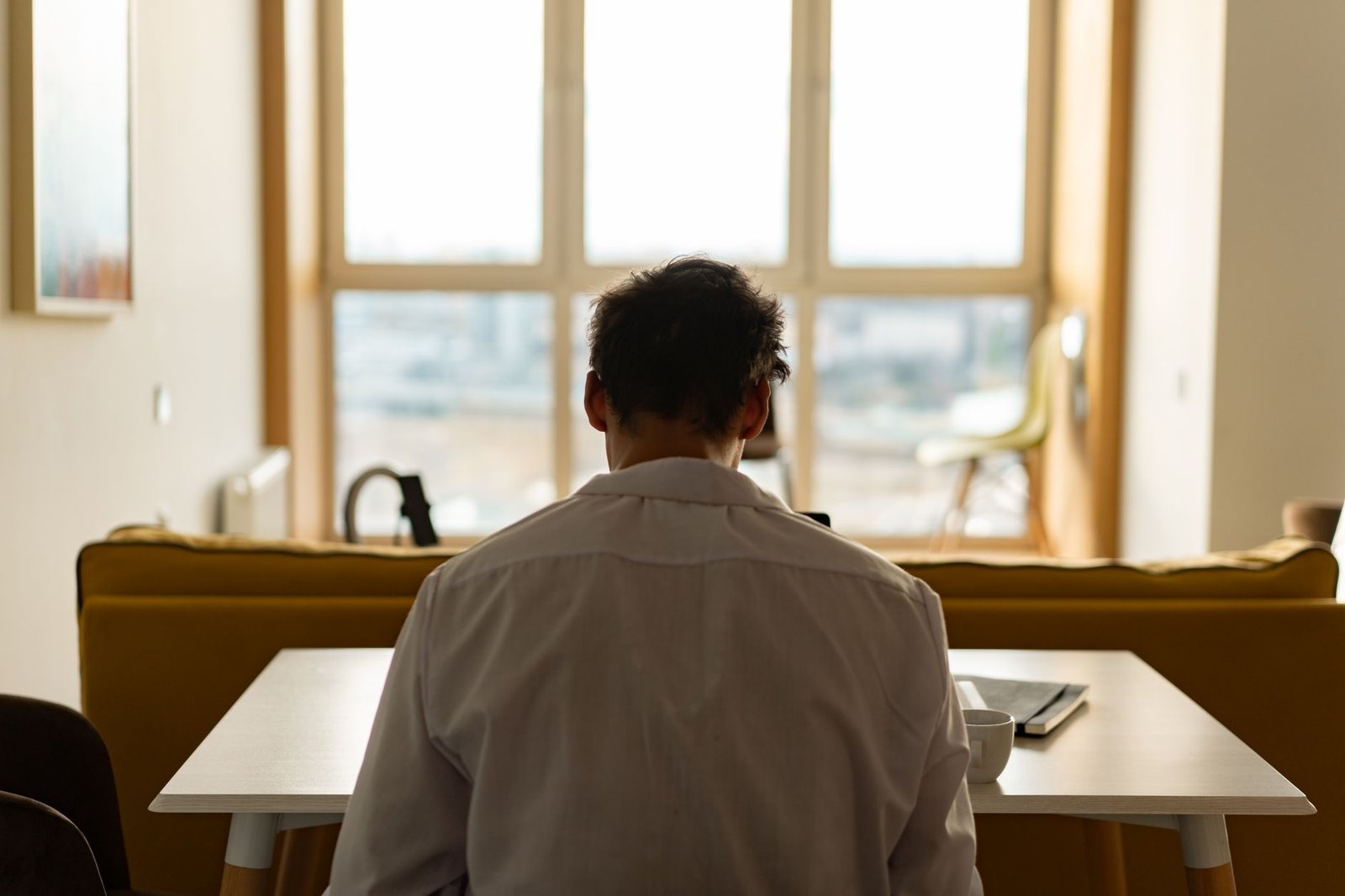 How to Choose a Virtual IOP in Indiana Around Shift Work 7 Back view of a man sitting at a desk, wearing a white shirt, with a window view.