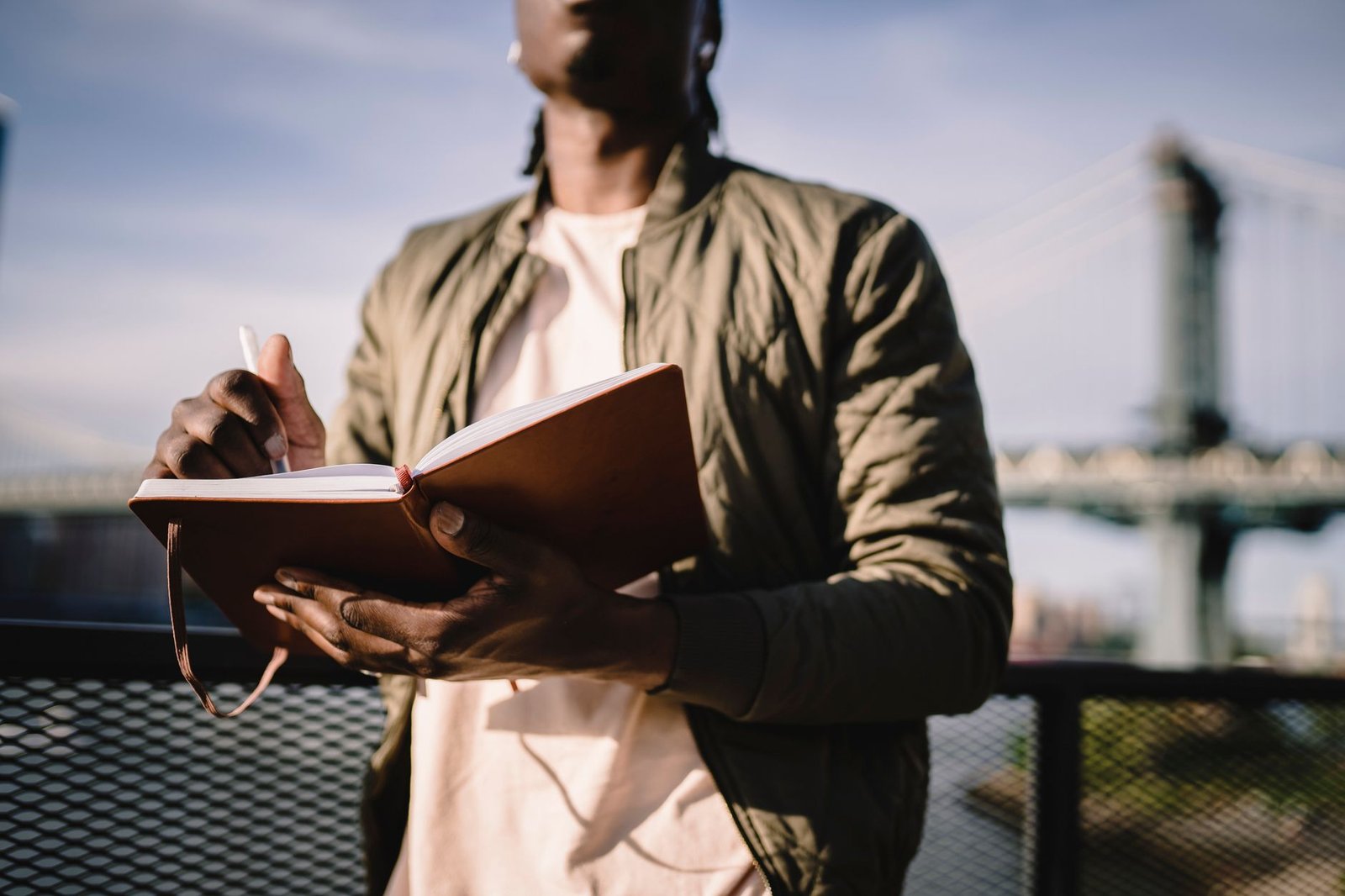 16 Emotion Regulation Activities for Adults, From a Clinical Team 6 From below of crop anonymous African American male in casual clothes standing near terrace fence with open journal and pen behind bridge over river in daylight