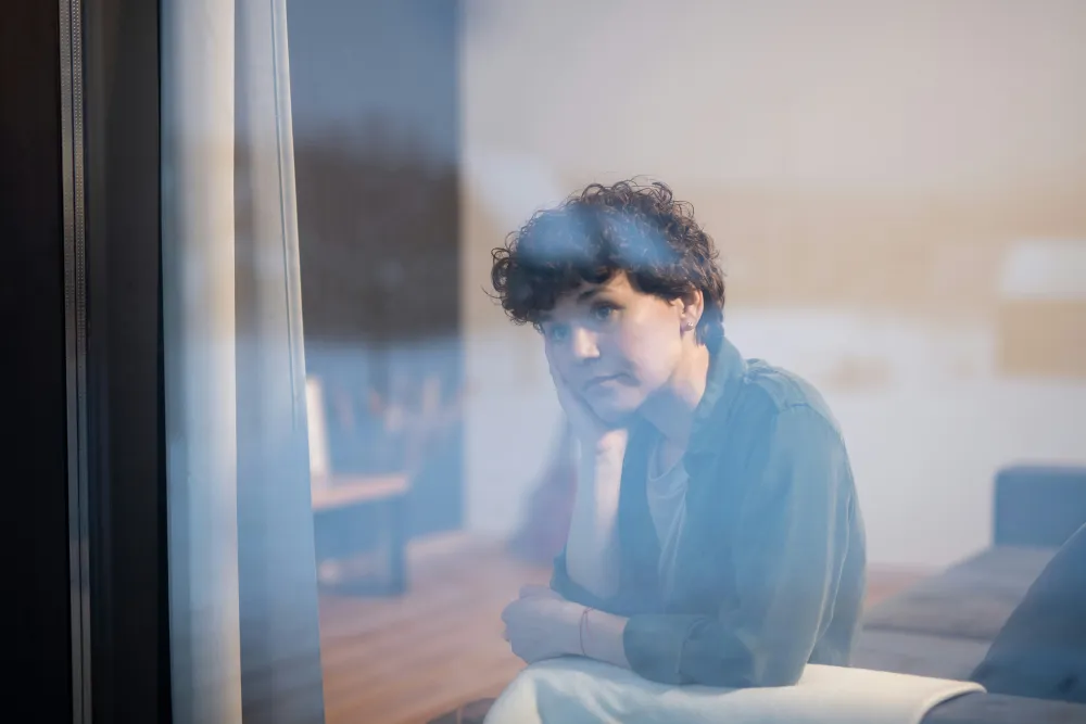 Young woman looking out a window, thinking