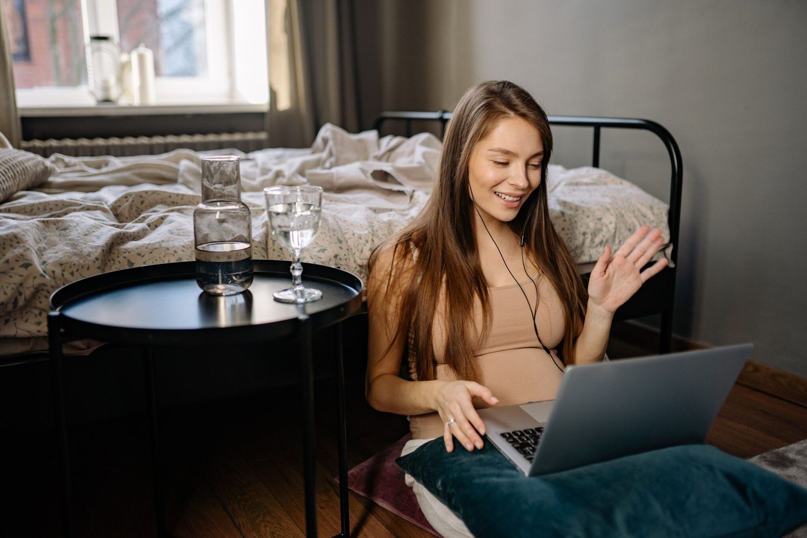 Adult waving hello on a laptop video call during a virtual IOP group session