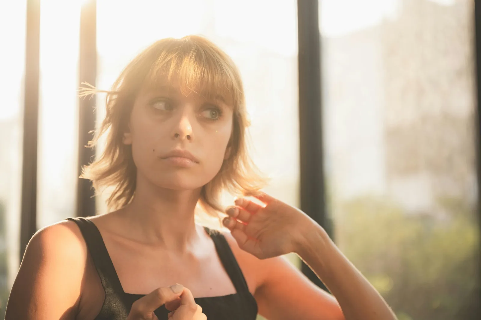 Young adult by a bright window at home, a quiet moment before her session