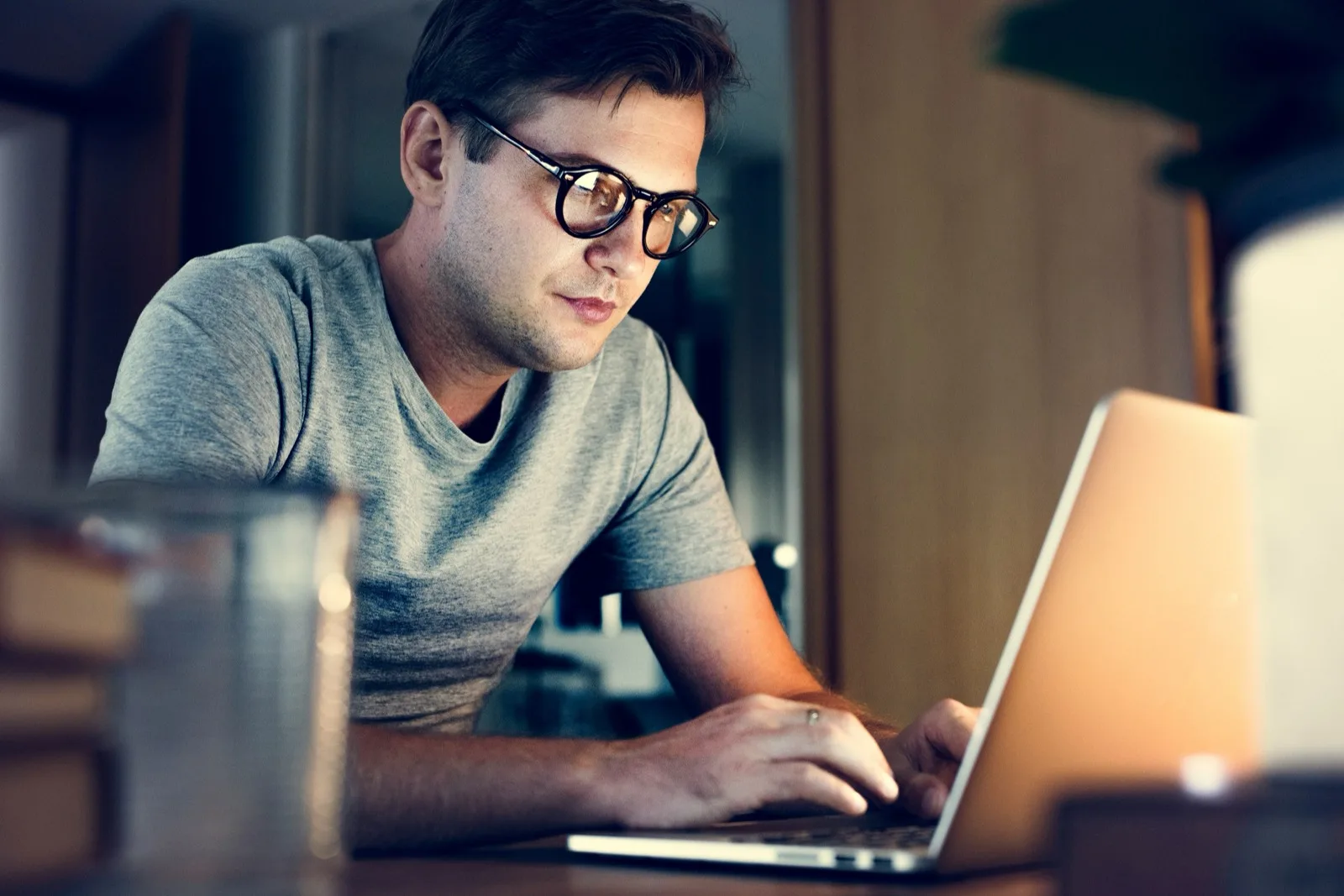 Young adult at his laptop at home in warm light, joining a session