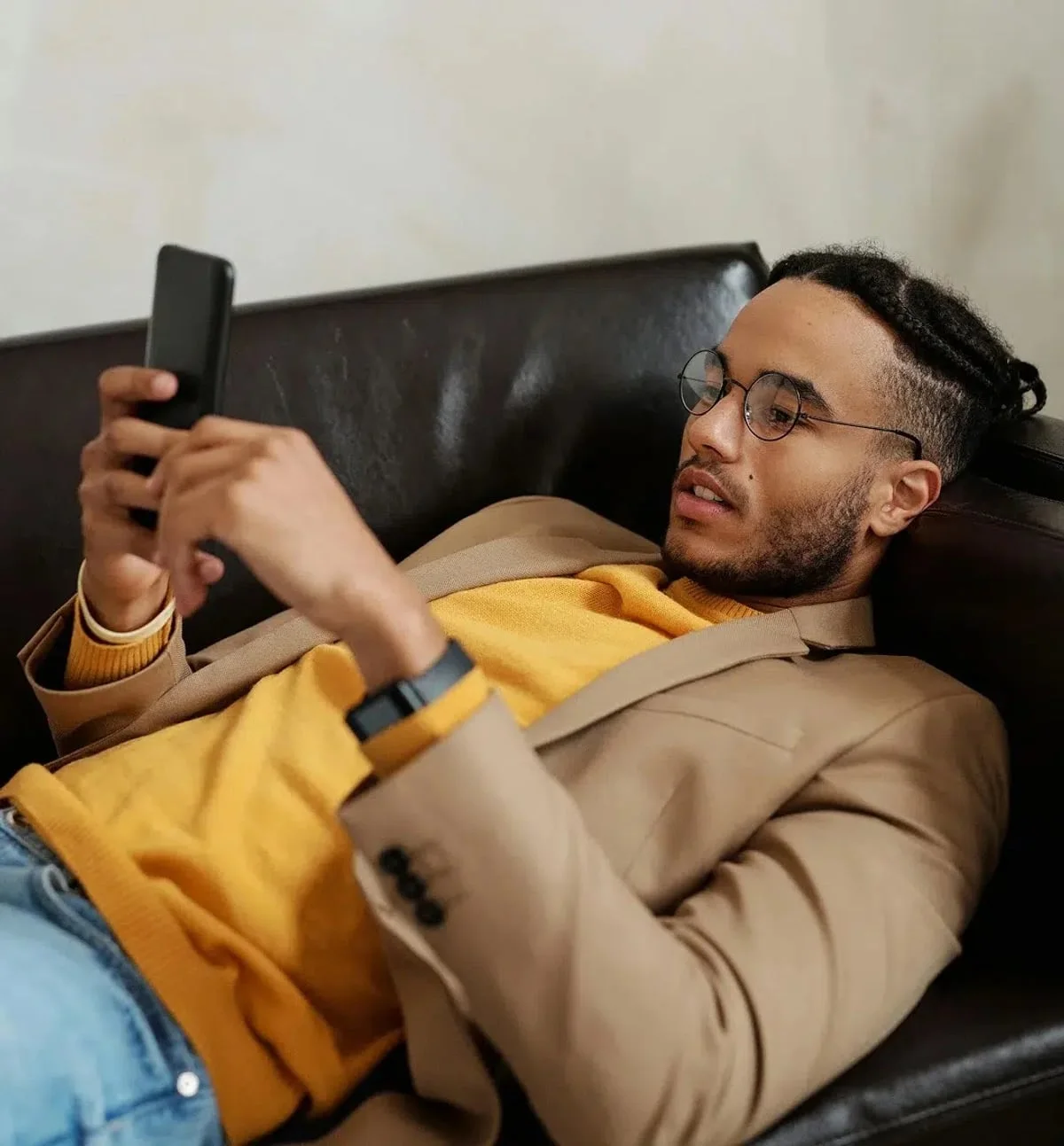 Adult relaxing on the couch at home, checking his coverage on his phone
