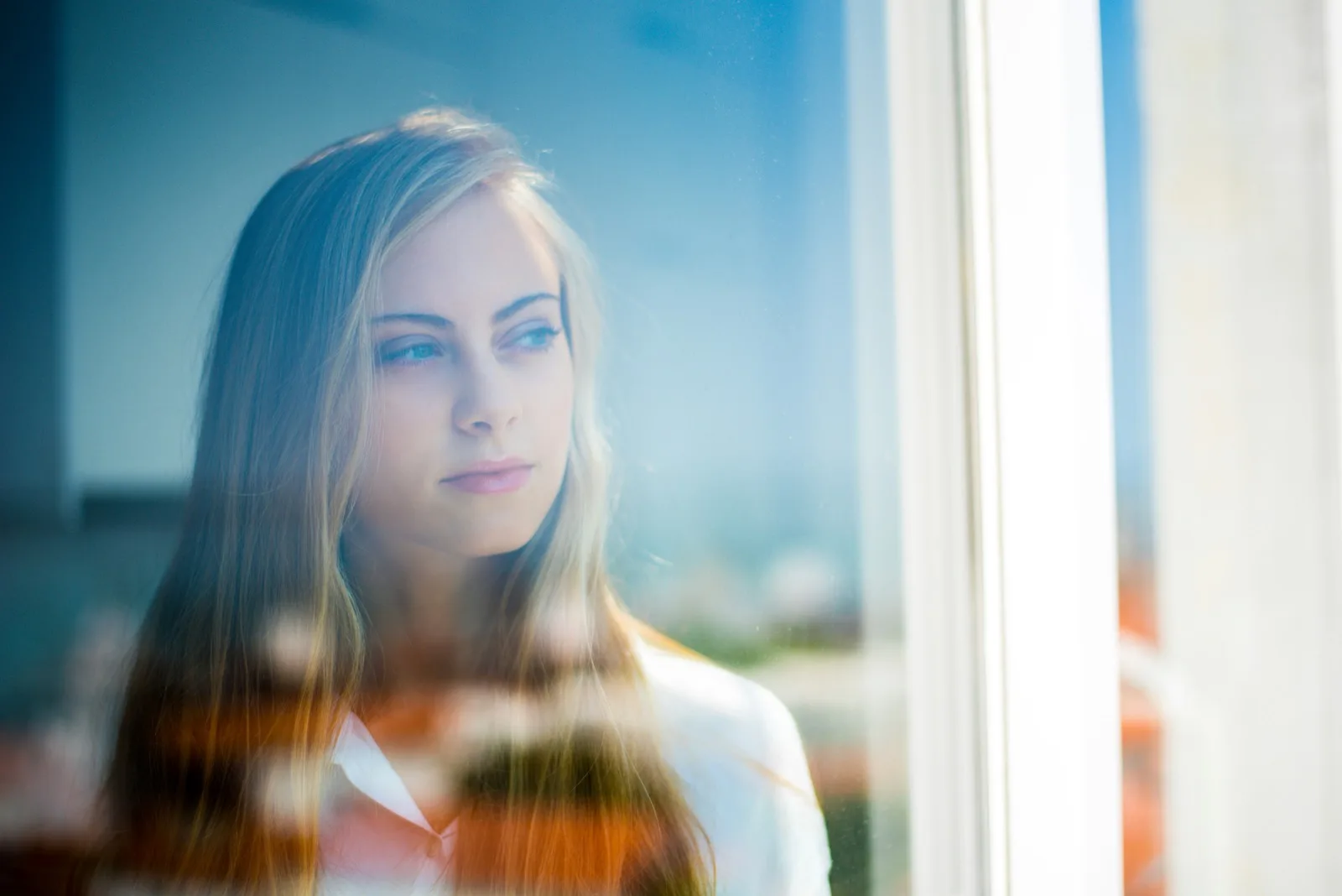 Young adult looking out of a window at home