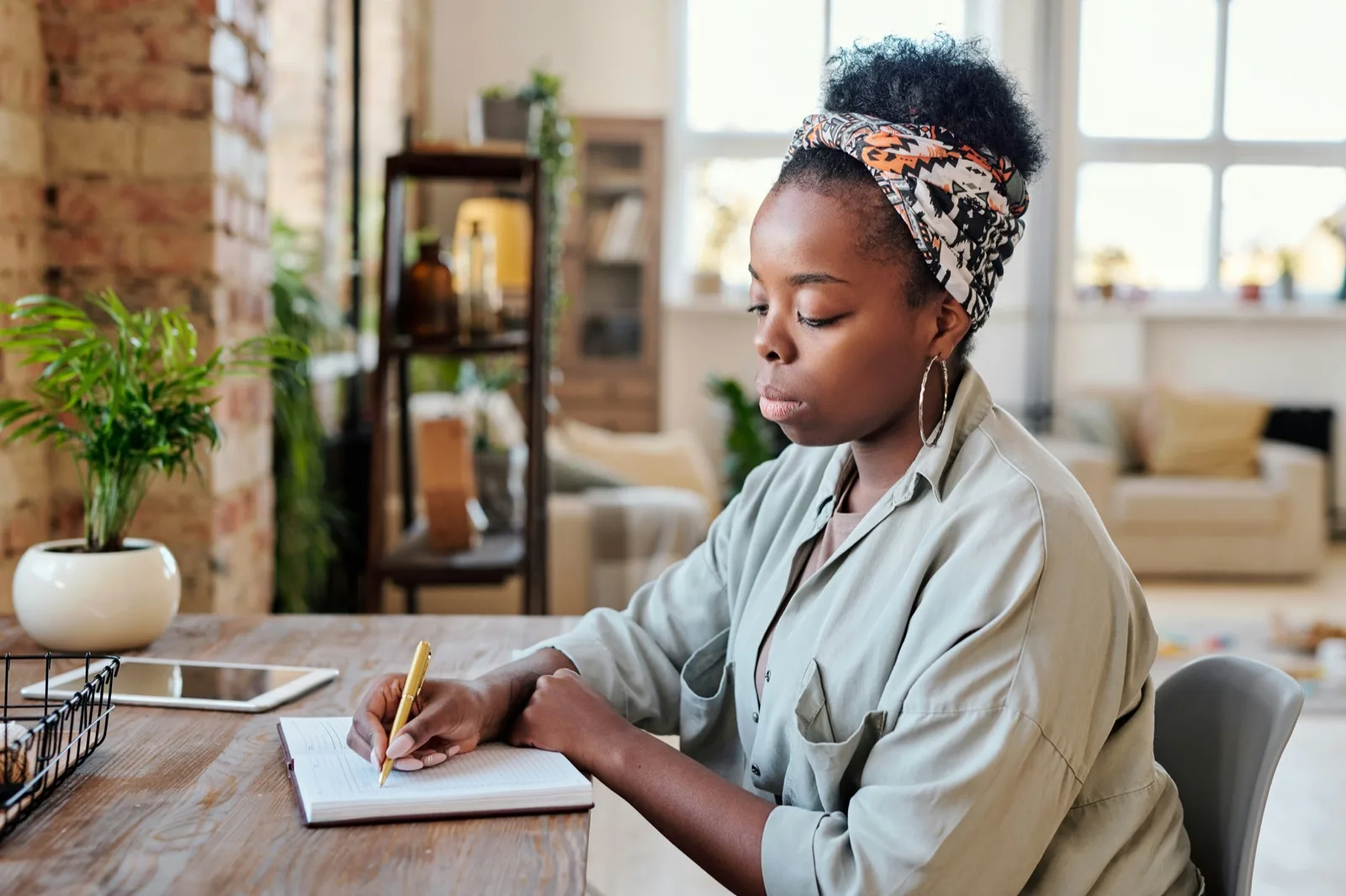 Adult making notes at a wooden desk at home