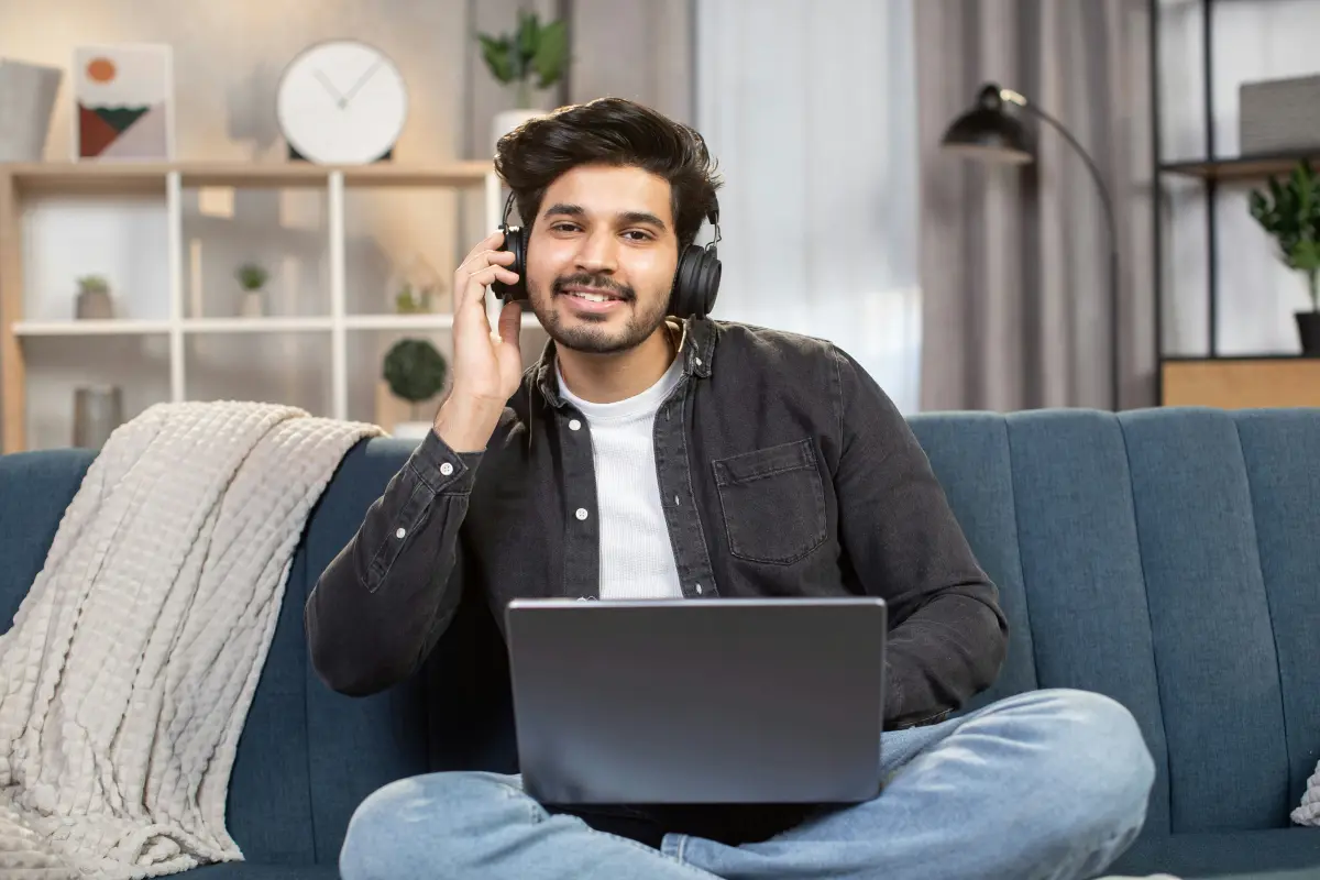 A man in headphones joining a session from his sofa