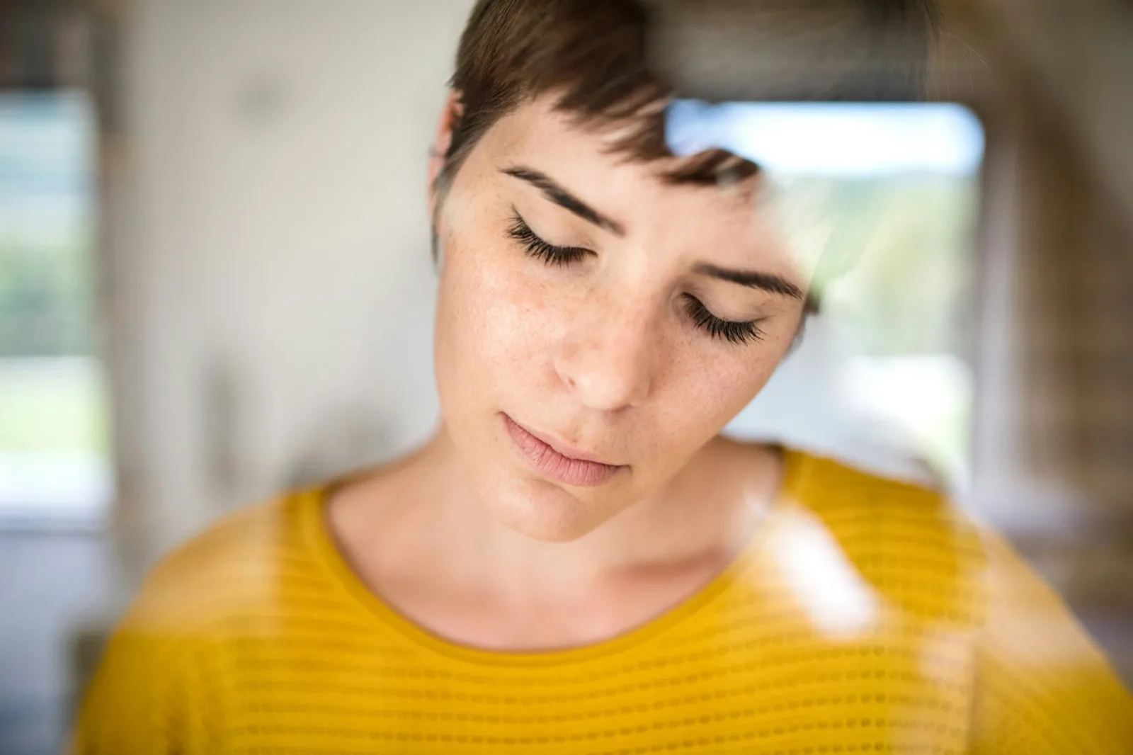 Young adult looking down, taking a quiet moment at home