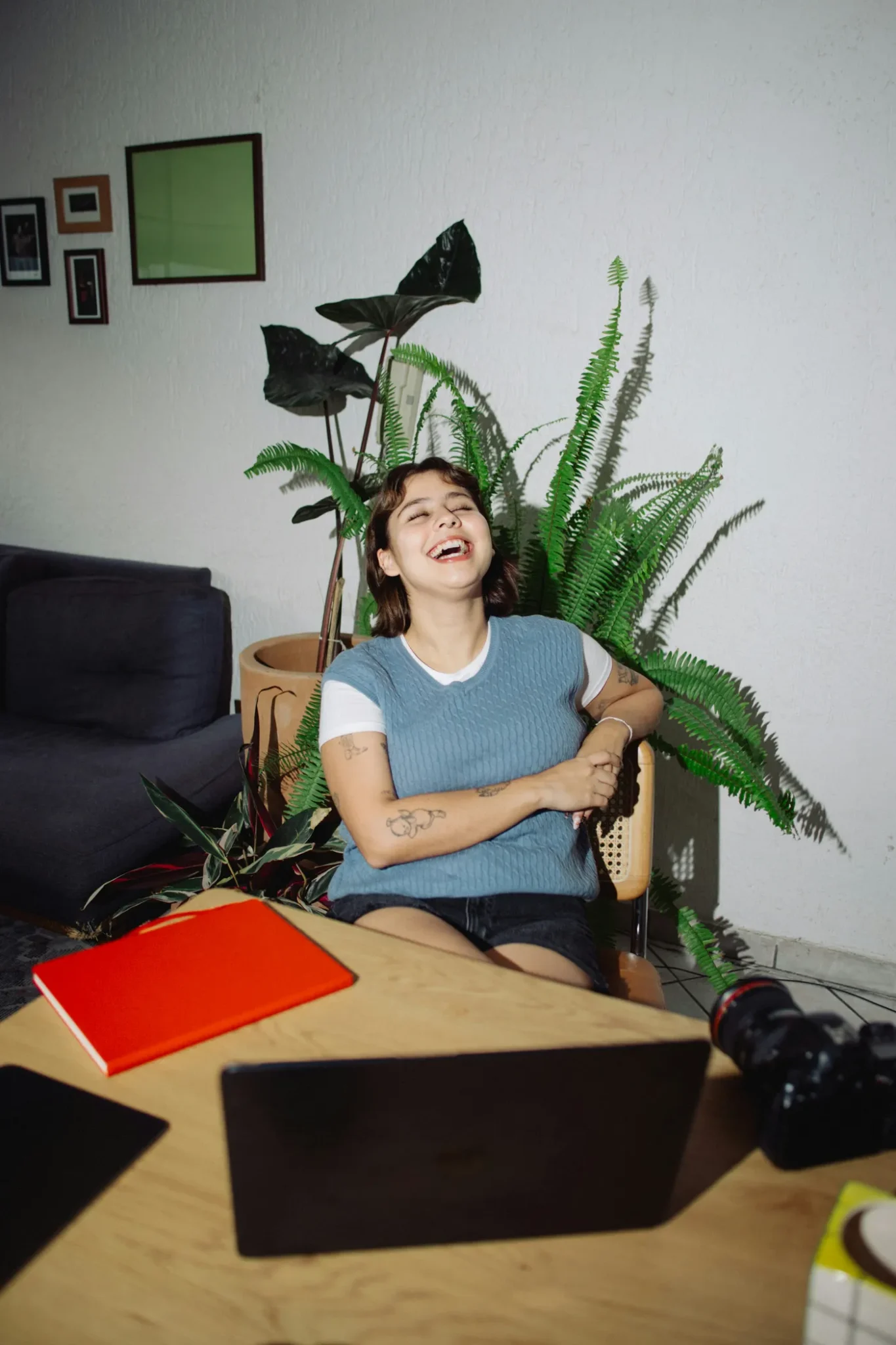 A woman laughing in a sunny room full of plants