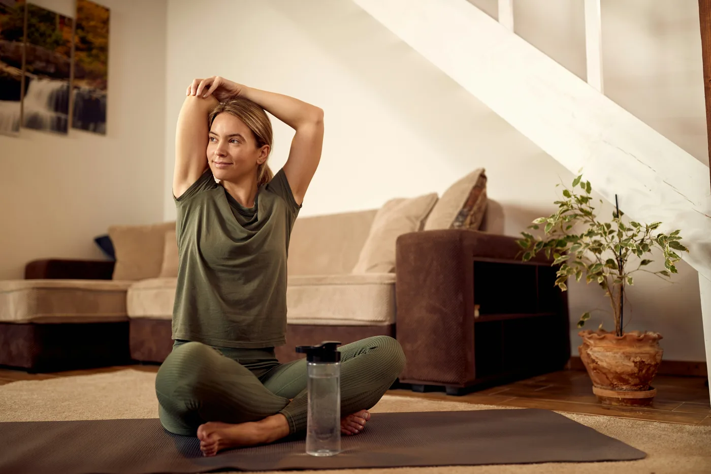 A smiling woman stretching on a yoga mat in her living room