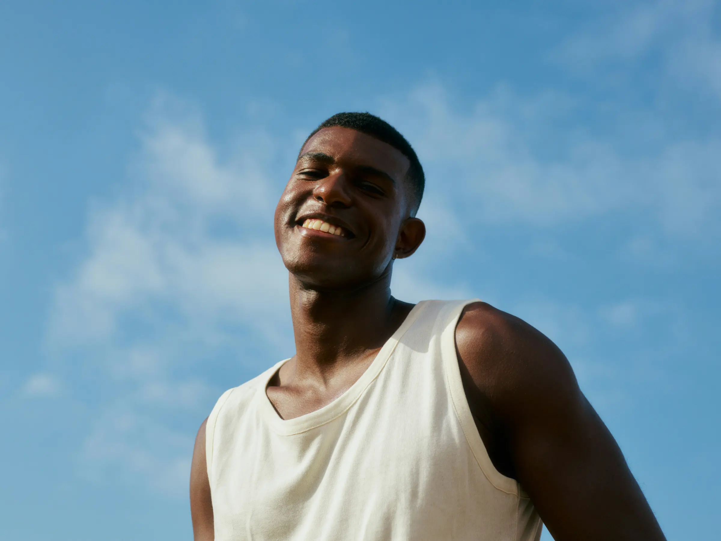 Man smiling outdoors under a blue sky