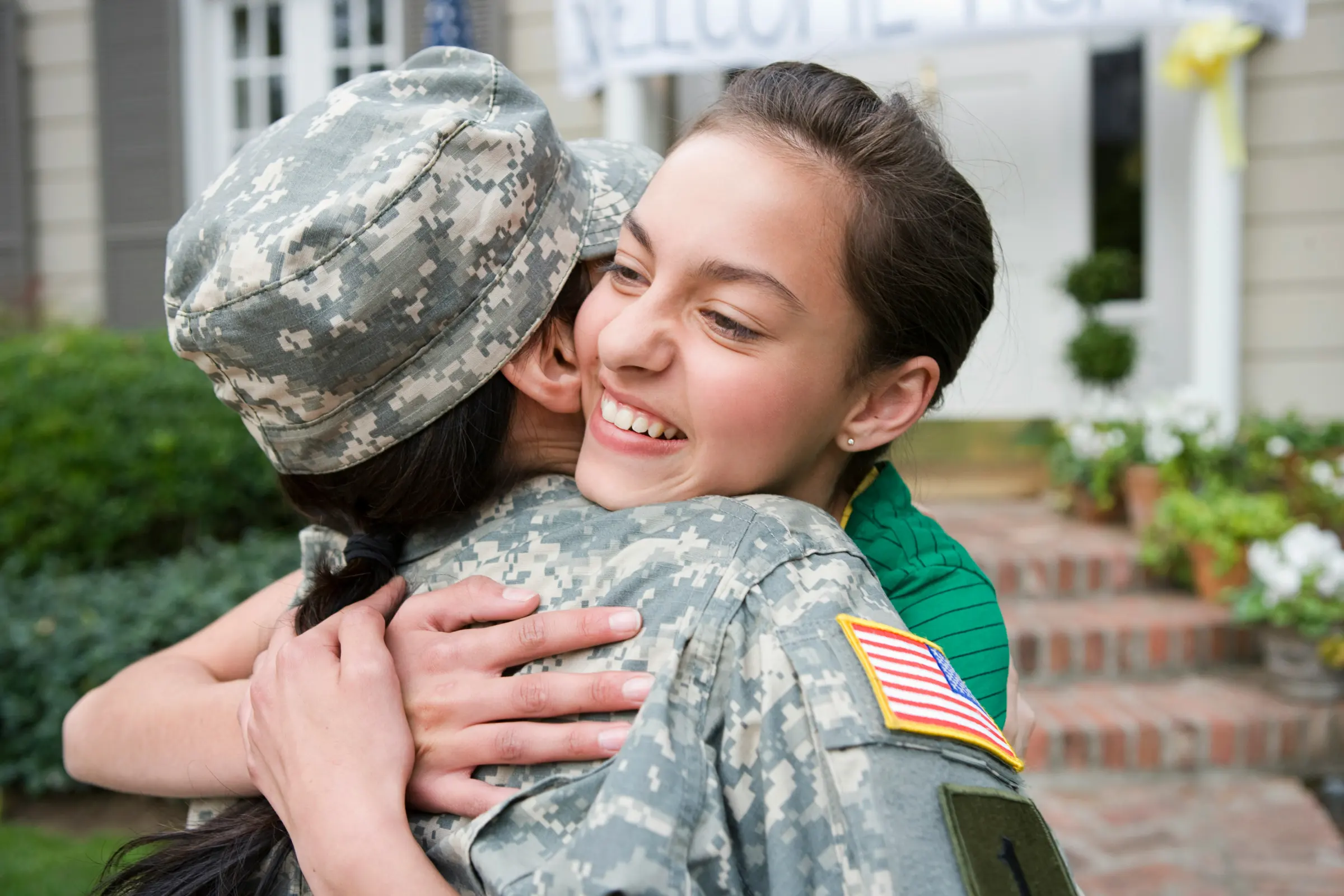 Service member in uniform hugging a smiling family member